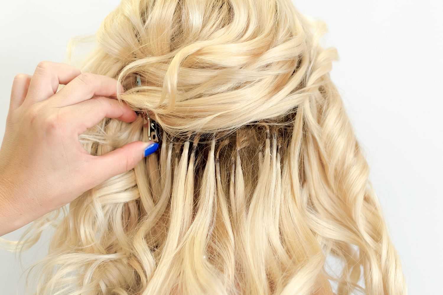 Person styling blonde hair with hair extensions and a clip.